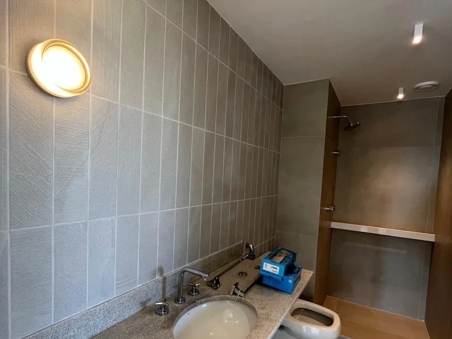 Banheiro reformado com bancada em pedra e box amplo, obra da Apto Engenharia na Barra da Tijuca